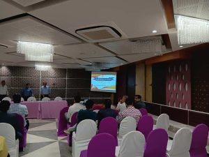 Members of Dariyapuri Sthanakwasi Jain Samiti attending a community meeting in Ahmedabad, with a presentation displayed on screen in a decorated hall.
