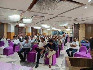 Audience seated on purple chairs during a Jain Samiti community event in Ahmedabad, attentively listening to discussions in a well-lit hall with chandeliers.