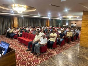 Audience seated on red chairs during a Dariyapuri Sthanakwasi Jain Samiti community gathering in Ahmedabad, listening to a presentation in a decorated hall.